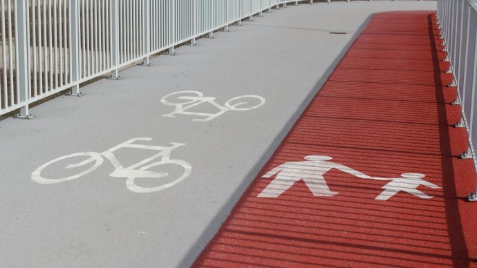 Sidewalk with painted concrete, showing pedestrians on right hand site an bikes on left hand side.