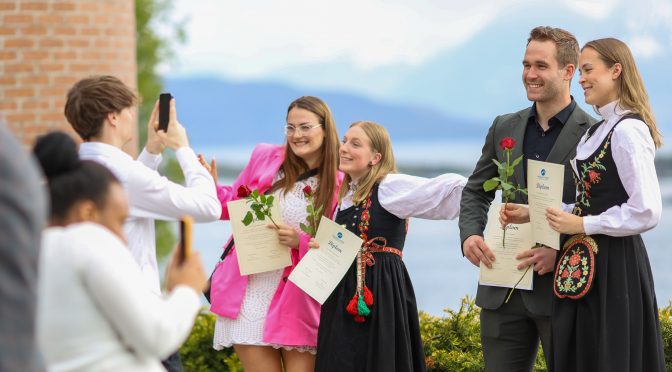 Glade studenter med vitnemål i hendene utenfor Høgskolen i Molde. 