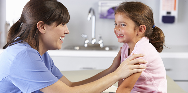 Foto av helsesykepleier som smiler og holder rundt skuldrene til ei ung jente.